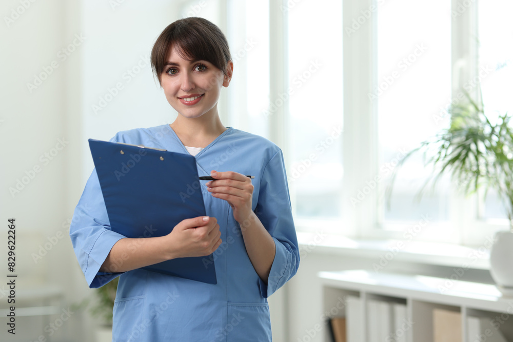 Portrait of smiling medical assistant with clipboard and pen in hospital. Space for text Portrait of smiling medical assistant with clipboard and pen in hospital. Space for text