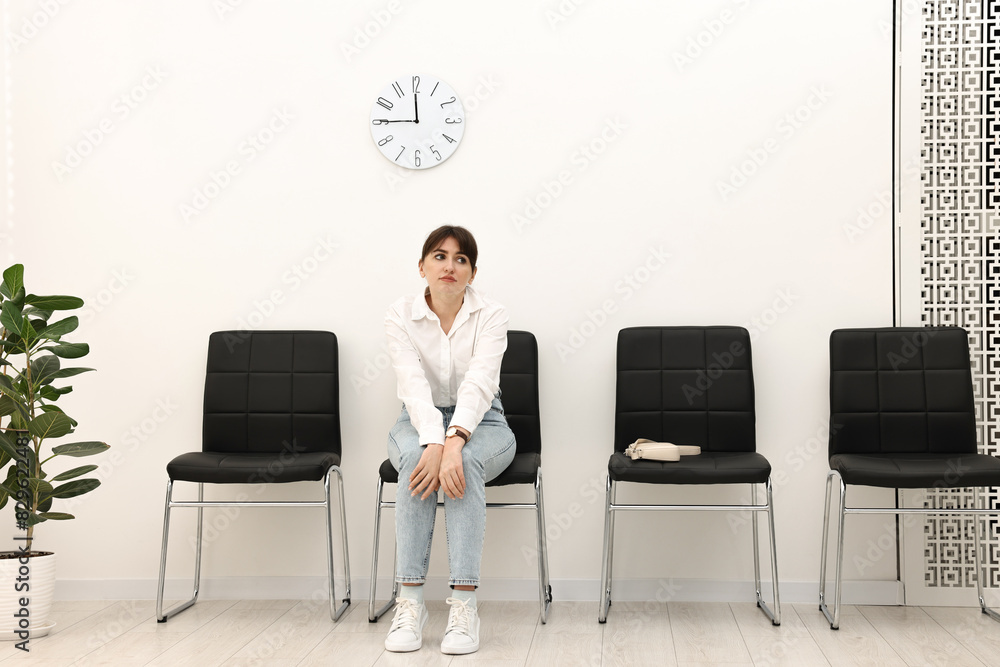 Woman sitting on chair and waiting for appointment indoors Woman sitting on chair and waiting for appointment indoors