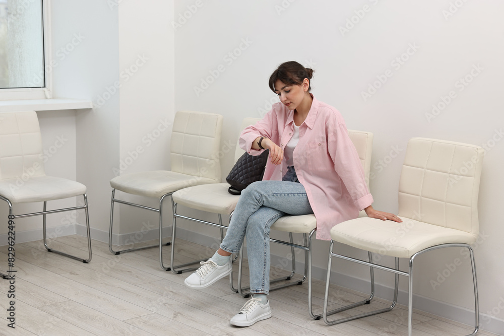 Woman looking at wrist watch and waiting for job interview indoors Woman looking at wrist watch and waiting for job interview indoors