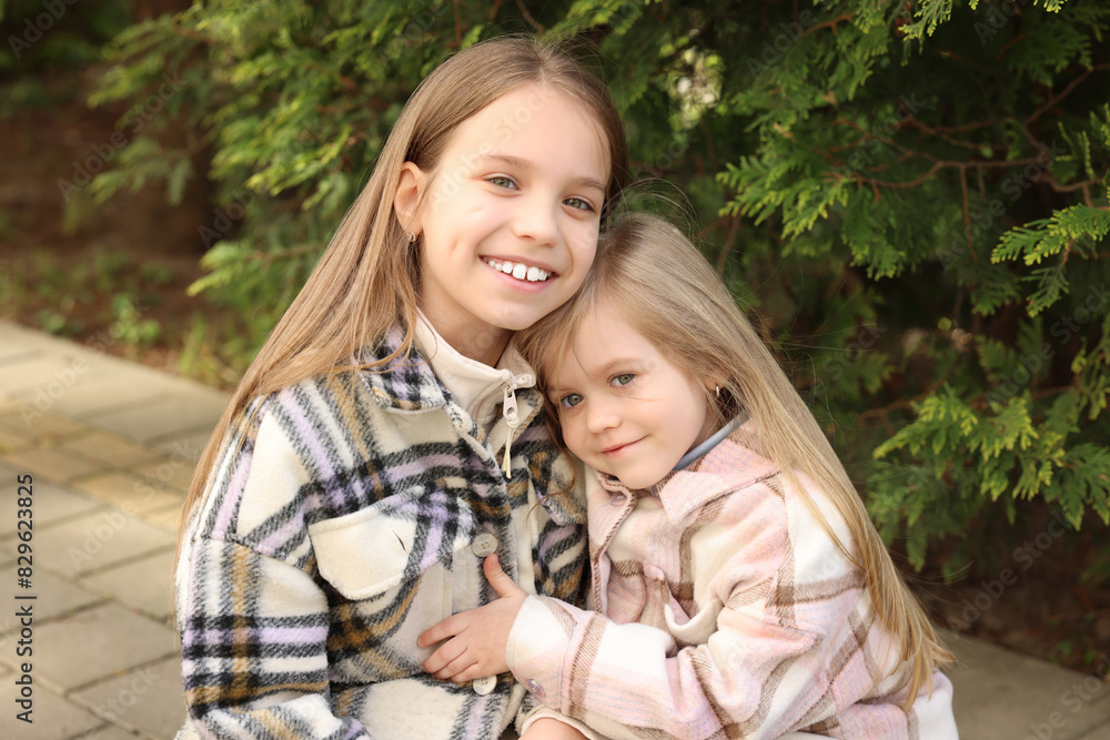 Cute little sisters spending time together outdoors Cute little sisters spending time together outdoors