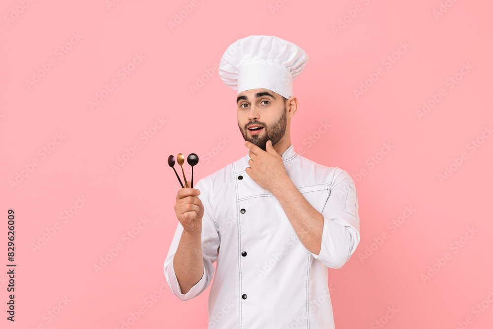 Professional chef holding kitchen utensils on pink background Professional chef holding kitchen utensils on pink background