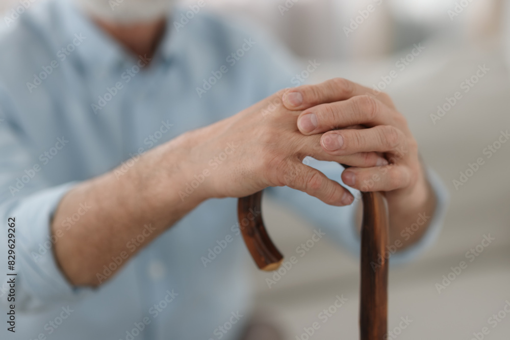 Obraz premium Grandpa with wooden walking cane indoors, closeup