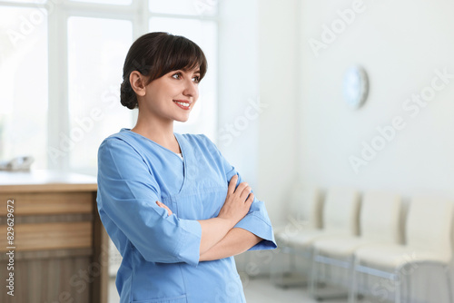 Free Download Portrait of smiling medical assistant with crossed arms in hospital. Space for text - GFXLoad