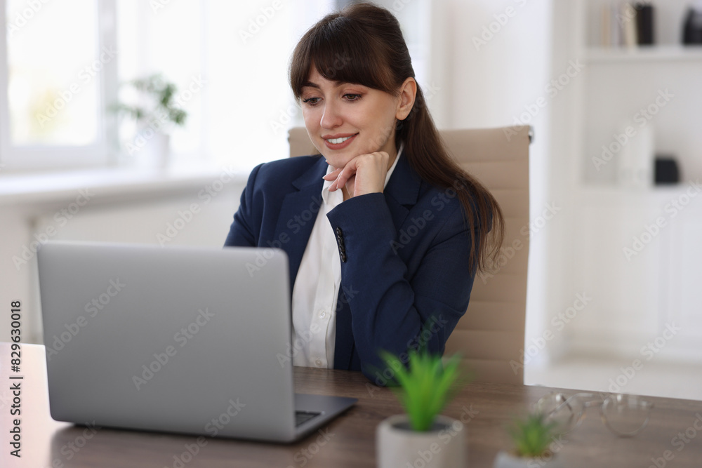 Woman watching webinar at wooden table in office Woman watching webinar at wooden table in office