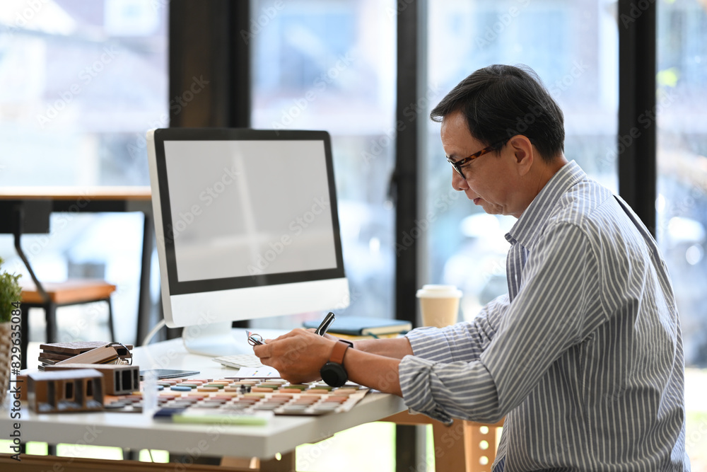 Side view senior architect working on new design project in the modern office Side view senior architect working on new design project in the modern office