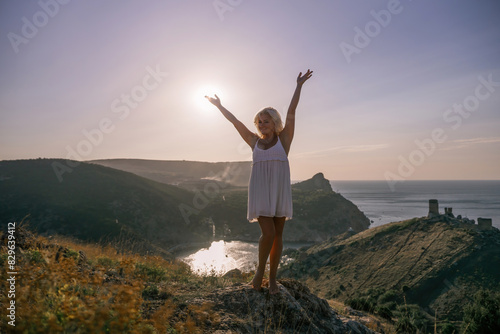 woman standing hill with her arms raised in the air, looking up at the sun. The scene is peaceful and serene, with the woman's expression conveying a sense of joy and happiness.