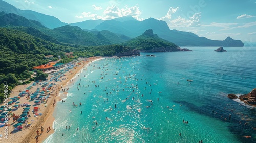 An aerial view of a bustling beach filled with people swimming and sunbathing, with mountains framing the scene photo