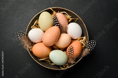 A bowl of raw chicken eggs. The food is enriched with protein. On a black stone background. Close up.