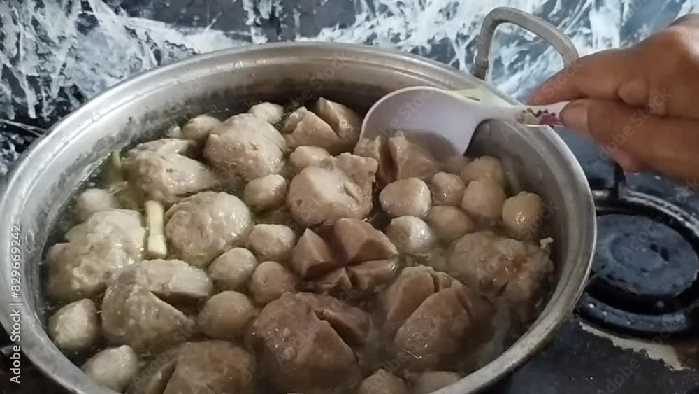 Round meatballs in a pan with lots of sauce are being stirred by buyers Round meatballs in a pan with lots of sauce are being stirred by buyers