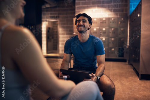 Laughing trainer doing a health questionnaire with a woman in a gym photo