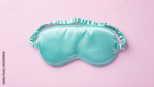 Turquoise silk sleep mask on pastel pink background