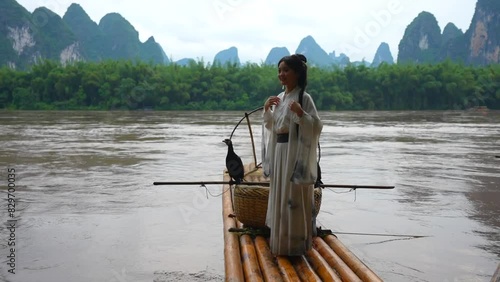 Cute Chinese Hanfu girl posing on bamboo raft in Li River, Xingping. Handheld photo