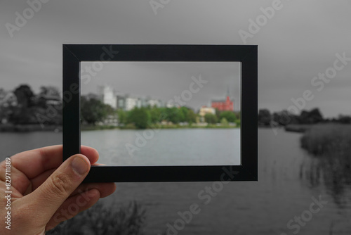 Cropped hand holding a photo frame against cityscape