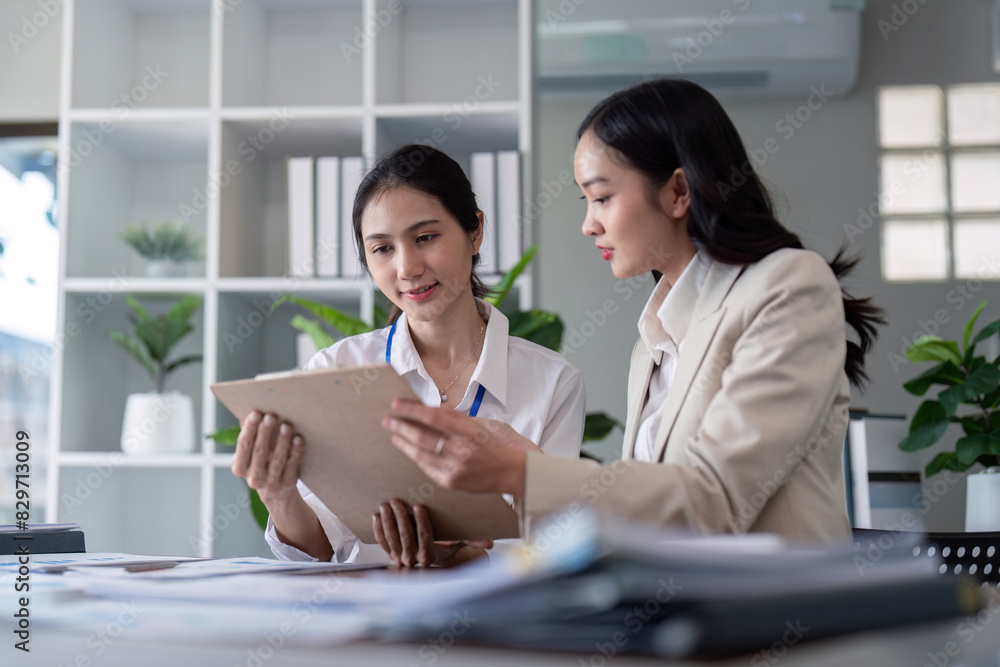 Businesswomen reviewing documents in modern office. Concept of teamwork and collaboration Businesswomen reviewing documents in modern office. Concept of teamwork and collaboration