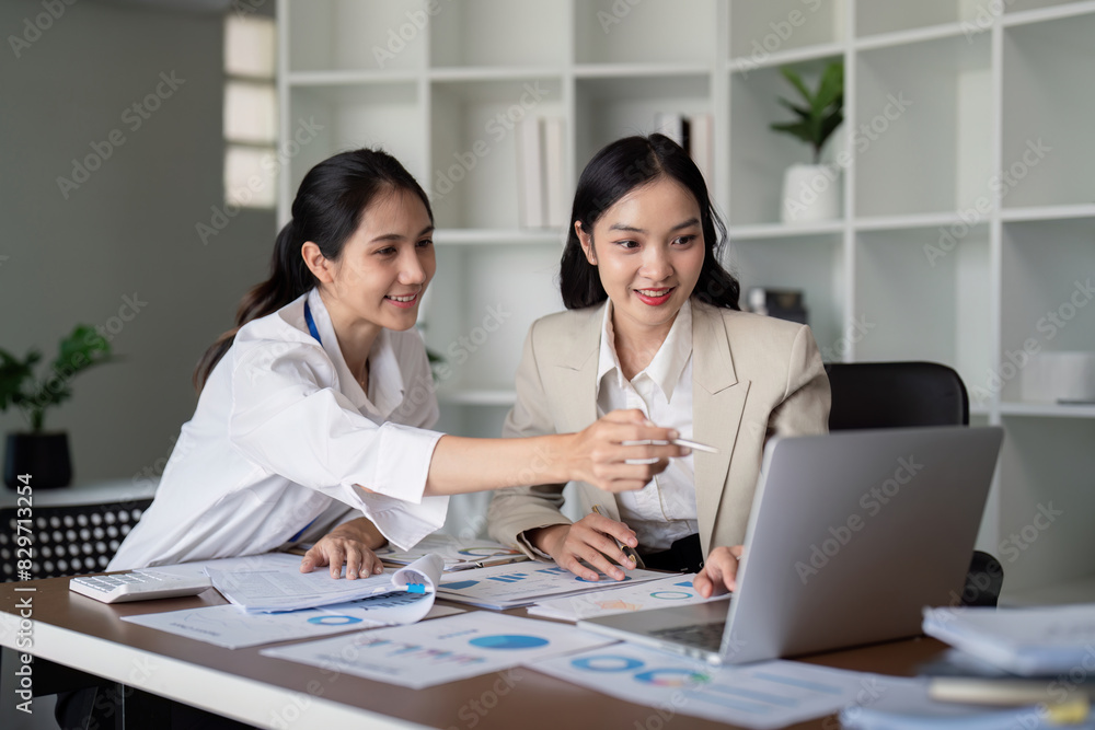 Businesswomen working on laptop and analyzing data in office. Concept of teamwork and collaboration Businesswomen working on laptop and analyzing data in office. Concept of teamwork and collaboration