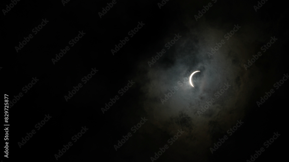 Fototapeta premium Solar eclipse with the moon shining through dark clouds in Waco, Texas