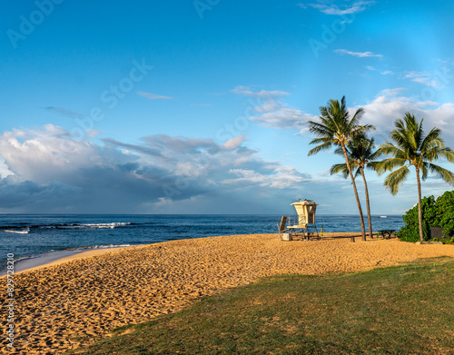 A white lifeguard shake guarding a swimming beach with coconut trees and grass by a clean blue ocean, Poipu Beach, Kauai photo