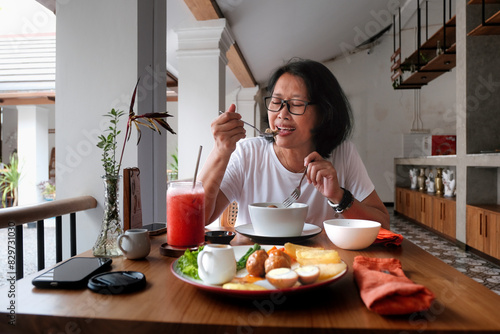 Woman eating alone in a small opened kitchen restaurant photo