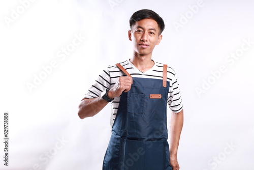 Asian Man wearing Apron in casual stylish clothing, standing upright pose while wearing and tidying his apron, isolated white background photo