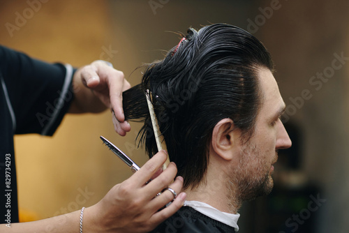 Hands of hairdresser trimming layered haircut photo