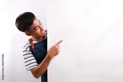 Happy Asian man in apron pointing something on white advertisement board on white background