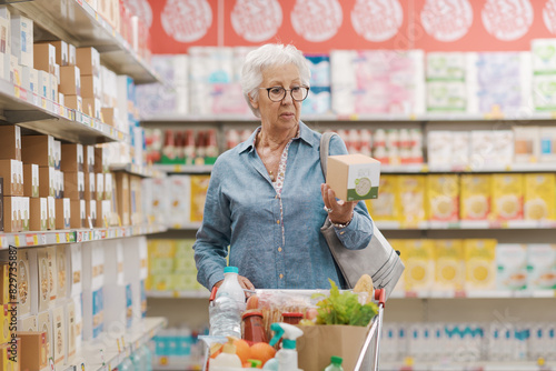 Senior woman reading information on a product package at the supermarket