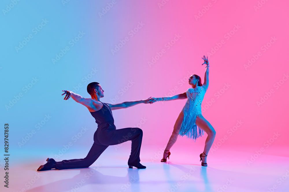 Ballroom dancers in perfect harmony, their fluid movements frozen in time in neon lighting against gradient background. Concept of dance and music, professional sport, action, competition, classical.