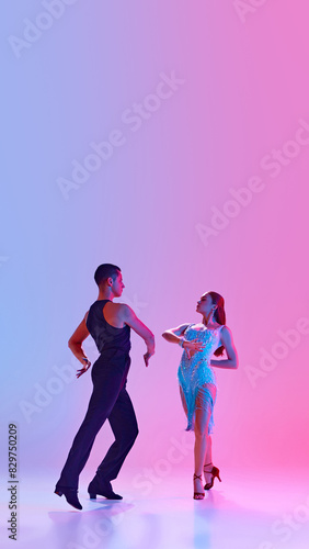 Poster. Young man and woman, ballroom dancers in stage costumes dancing tango energetically in neon lighting against gradient background. Concept of dance and music, sport, action, competition. Ad