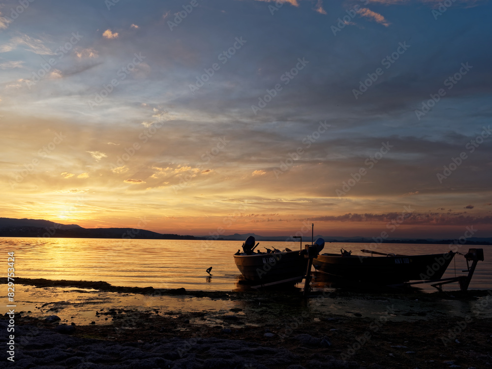 Golden light of the sunset illuminates the lake and some boats on the shore Golden light of the sunset illuminates the lake and some boats on the shore