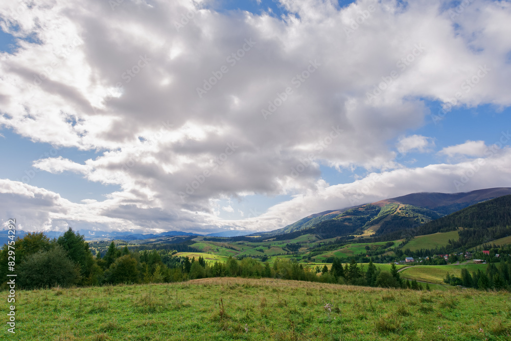 rural landscape in carpathian mountains of ukraine. alpine countryside scenery with grassy meadows and forested rolling hills in autumn. beautiful view of the valley near borzhava ridge on a sunny day