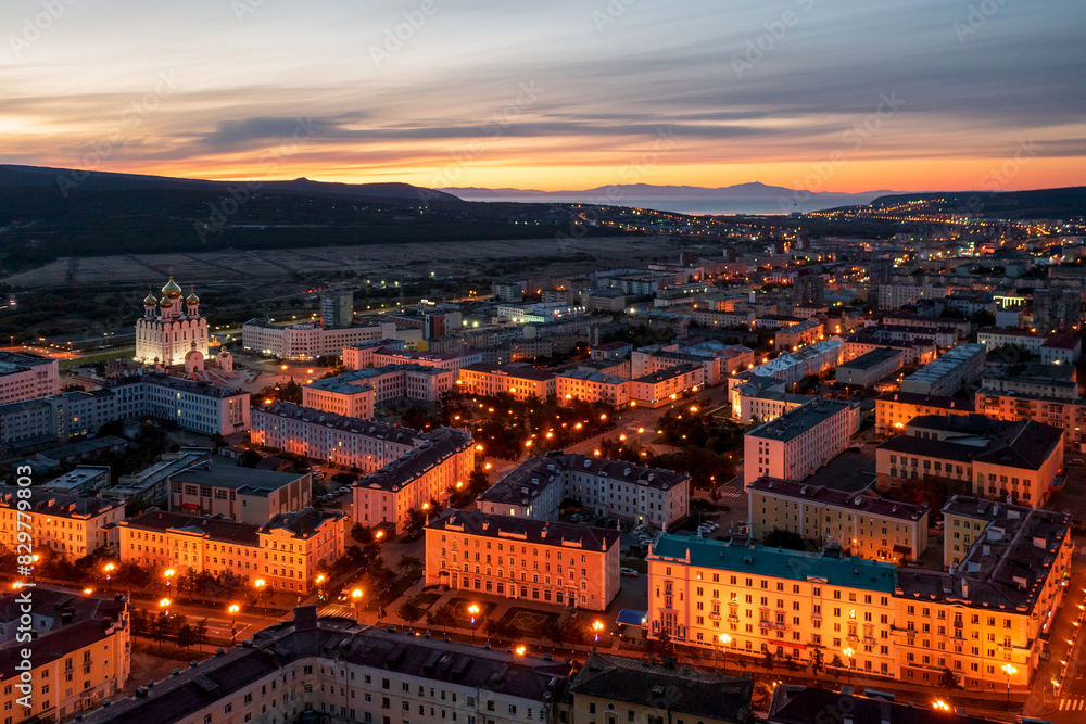 Aerial view of the city of Magadan. Beautiful night cityscape. Top view of the streets and buildings. In the distance is a sea bay. Early morning, dawn. Magadan, Magadan region, Russian Far East.