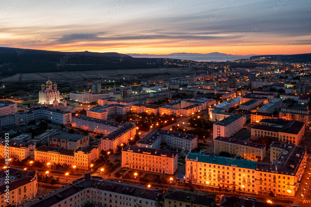 Obraz premium Aerial view of the city of Magadan. Beautiful night cityscape. Top view of the streets and buildings. In the distance is a sea bay. Early morning, dawn. Magadan, Magadan region, Russian Far East.