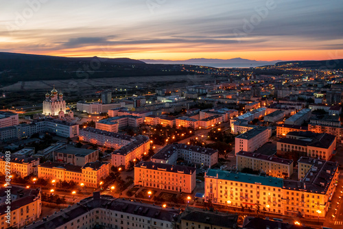 Aerial view of the city of Magadan. Beautiful night cityscape. Top view of the streets and buildings. In the distance is a sea bay. Early morning, dawn. Magadan, Magadan region, Russian Far East.