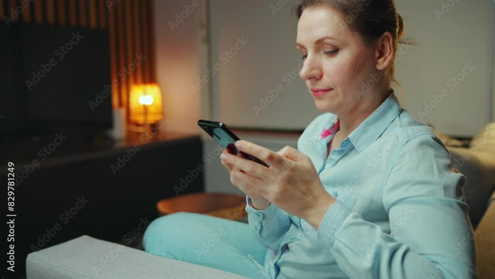 A woman is comfortably texting on her smartphone at home in a relaxed atmosphere A woman is comfortably texting on her smartphone at home in a relaxed atmosphere
