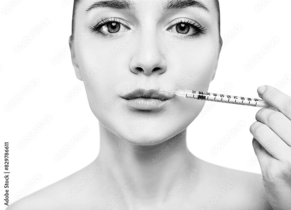Obraz premium Young woman gets cosmetic injection in lips.