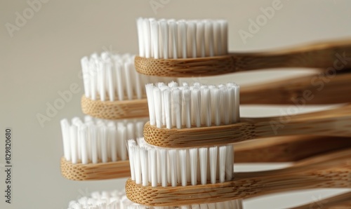 stack of bamboo toothbrushes with white bristles on neutral background