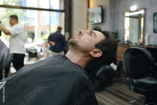 Man resting in styling chair waiting for barber © DragonImages