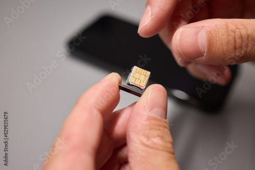 A person is inserting a sim card into a cell phone using hand and fingers