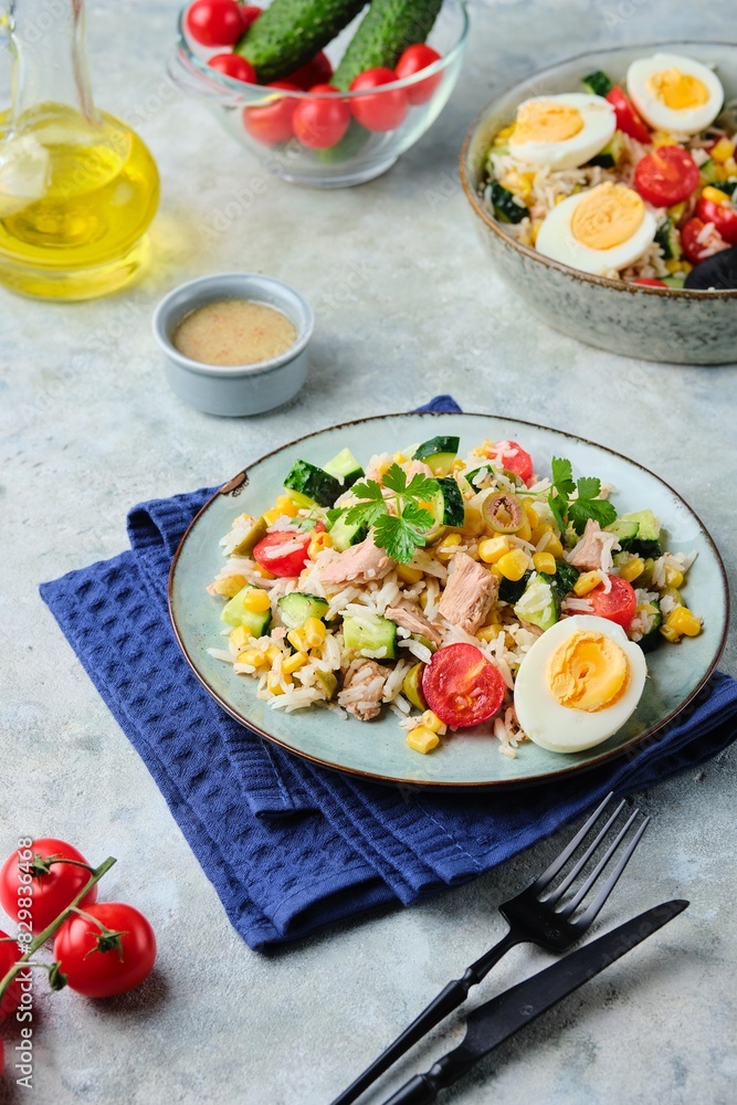 French rice salad with canned tuna, cherry tomatoes, corn and cucumber on a ceramic plate on a gray concrete background. Summer Picnic salad. French rice salad with canned tuna, cherry tomatoes, corn and cucumber on a ceramic plate on a gray concrete background. Summer Picnic salad.
