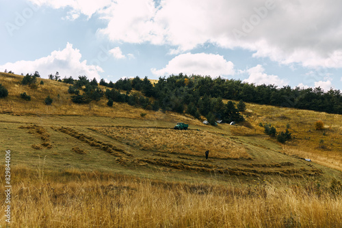 Photography Scenic rural landscape with a tractor and a green truck on a grassy hillside und