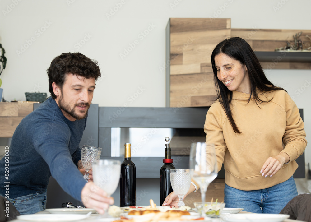 couple setting the table for lunch or dinner with guests. Cheerful caucasian couple setting cutlery for easter dinner. couple setting the table for lunch or dinner with guests. Cheerful caucasian couple setting cutlery for easter dinner.