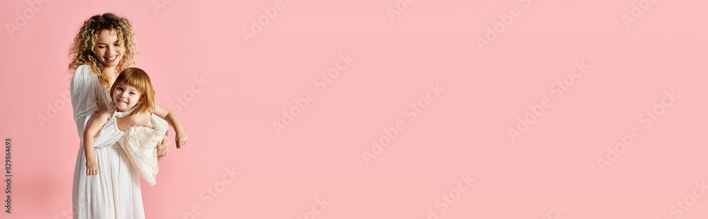 A woman holds a baby against a pink backdrop. A woman holds a baby against a pink backdrop.