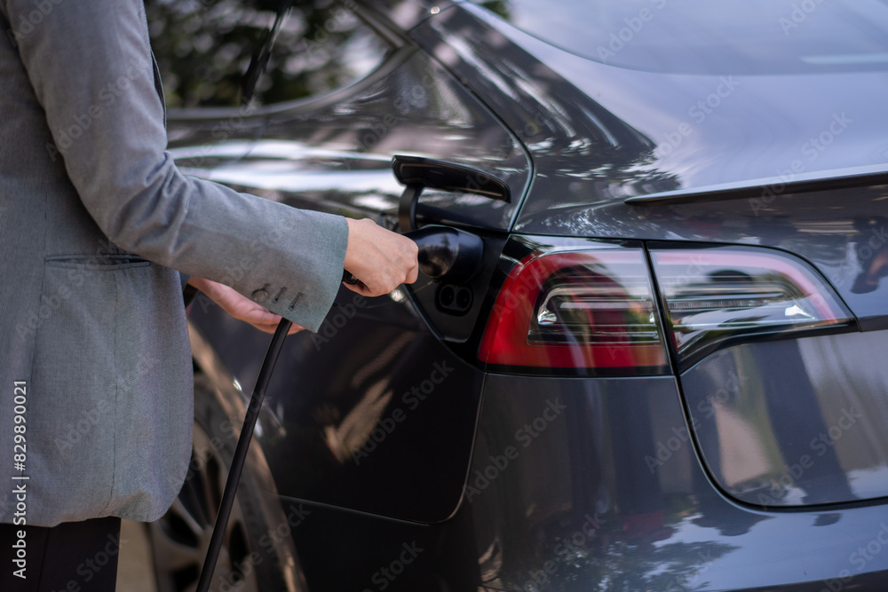 Fototapeta premium A woman is plugging in her car