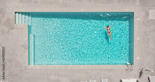 Top down view of a woman in redre swimsuit lying on her back in the pool. photo