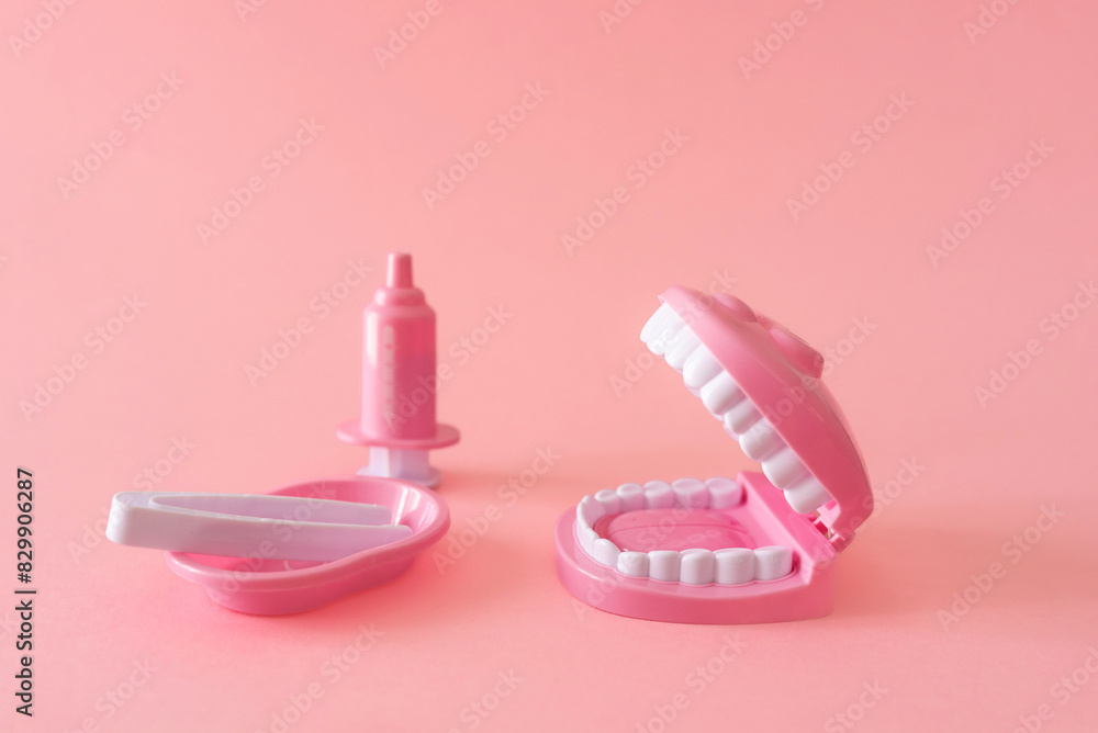 a pink dental model toy with open mouth and dental tools for infant dental care and hygiene on pink background a pink dental model toy with open mouth and dental tools for infant dental care and hygiene on pink background