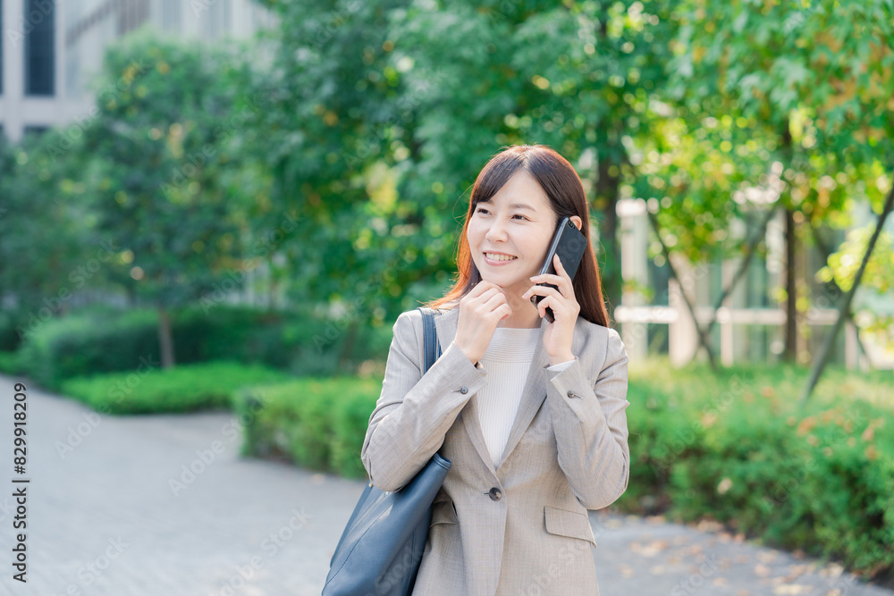 電話で話しながらビジネス街を歩くビジネスウーマン 電話で話しながらビジネス街を歩くビジネスウーマン