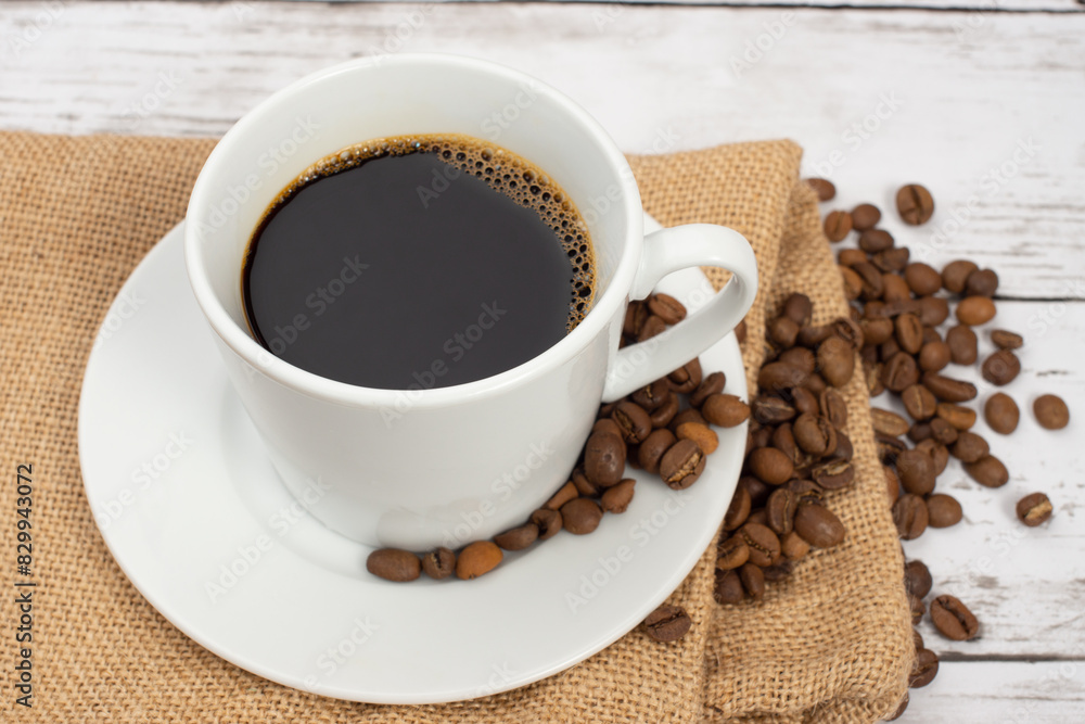 白い木目テーブルの上に置かれたコーヒーカップとコーヒー豆 白い木目テーブルの上に置かれたコーヒーカップとコーヒー豆