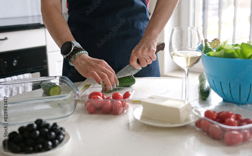 Woman'S Hands Are Slicing Cucumber For Greek Salad With A Glass Of White Wine Nearby Woman'S Hands Are Slicing Cucumber For Greek Salad With A Glass Of White Wine Nearby