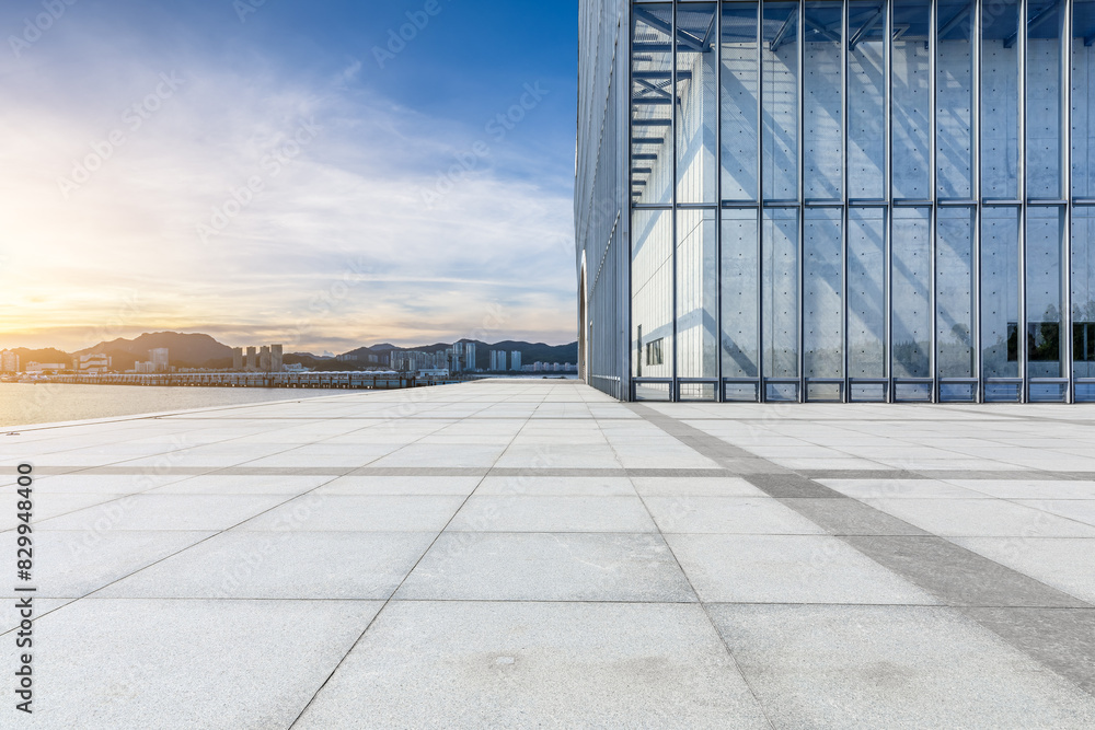 Empty square floor and glass wall with coastline at sunset