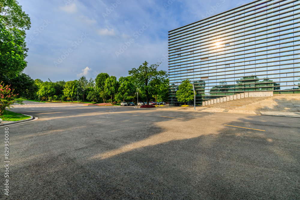 Asphalt road and green forest with glass wall building background in city park Asphalt road and green forest with glass wall building background in city park